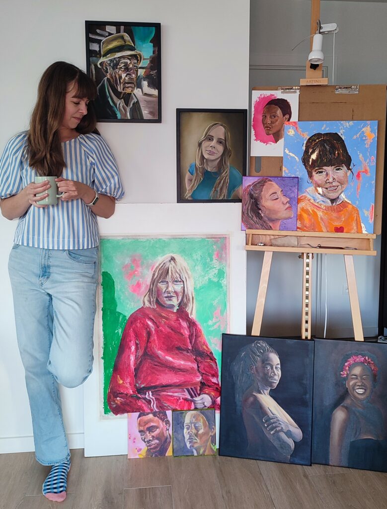 Kunstenares Wine Tess Art poseert bij haar olieverfportretten